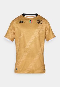 Zlatá futbalová dres s textúrovaným povrchom, čiernymi akcentmi, logom Kappa a emblemu talianskej vlajky. Má krátke rukávy a okrúhly výstrih.