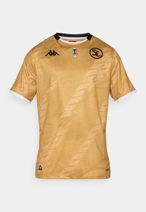 Zelta futbols krekls ar teksturētu virsmu, melniem akcentiem, Kappa logo un Itālijas karoga emblēmu. Ar īsām piedurknēm un apaļu kakla izgriezumu.