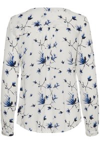 Blouse à manches longues en tissu blanc avec des motifs floraux bleus et des branches noires. Dotée d'un ourlet arrondi et de poignets boutonnés. Texture lisse.