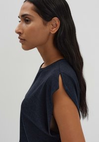 Haut à manches courtes bleu marine avec un col rond et des détails fendus aux épaules, fabriqué dans un tissu texturé.