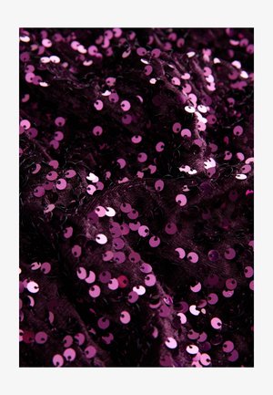 Lilla stof dækket med runde pink palietter, der skaber en tekstureret overflade. Palietterne reflekterer lys og tilføjer glans og dybde.