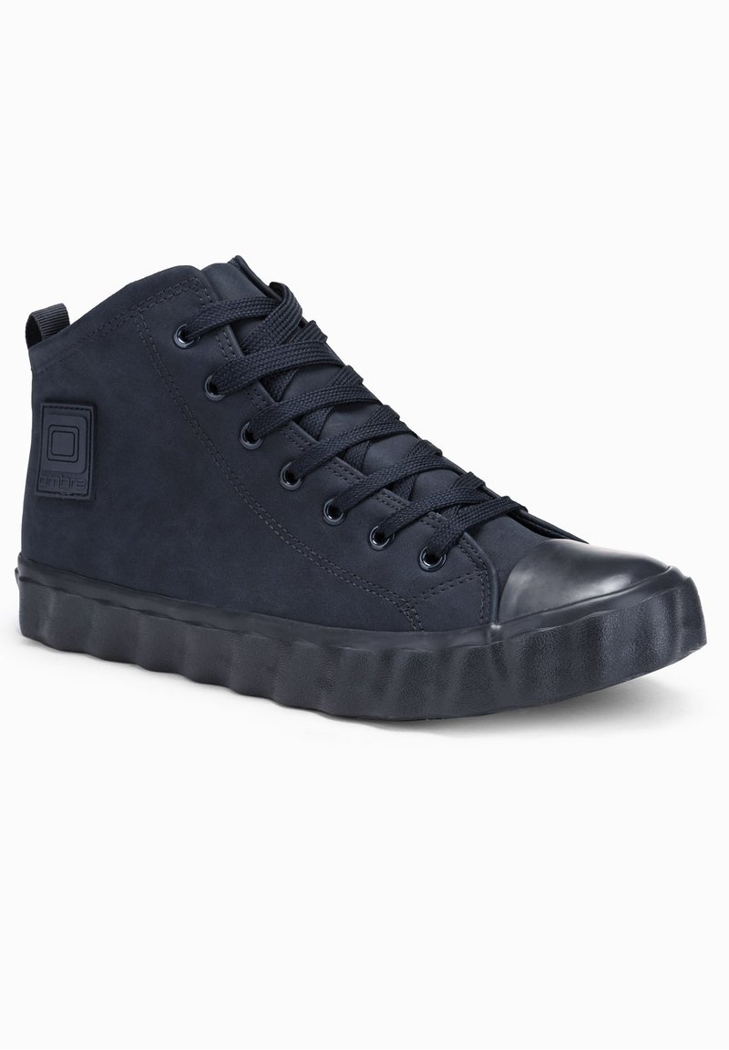 Baskets montantes noires avec semelle en caoutchouc épaisse, bout rond, fermeture à lacets et patch de marque sur le côté.