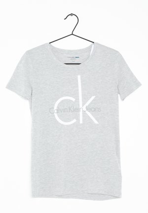 Šedé tričko s krátkým rukávem vyrobené z měkké látky, s velkým bílým logem "CK" a textem "Calvin Klein Jeans" potištěným uprostřed.