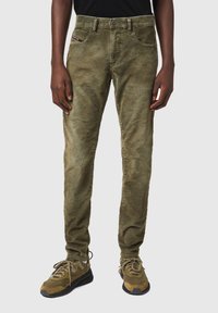 Pantalones de pana verde oliva con corte recto, diseño de cinco bolsillos y textura sutil. Combinados con zapatillas verde oliva.