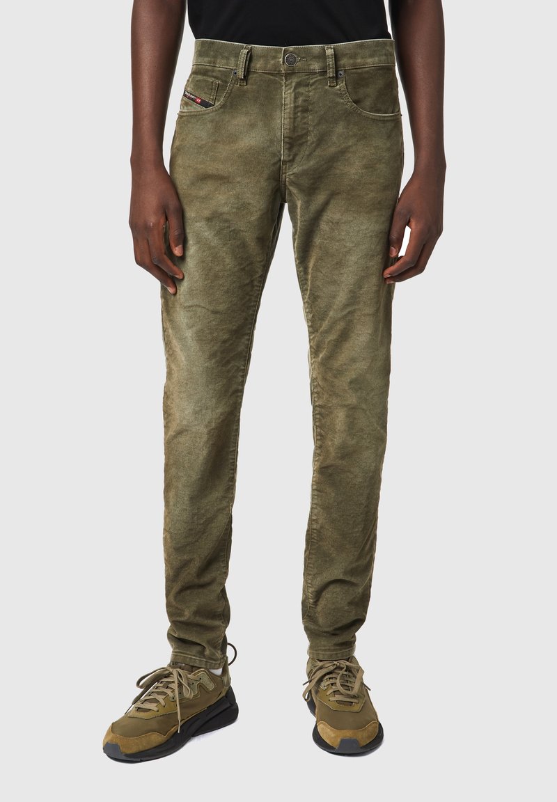 Pantalones de pana verde oliva con corte recto, diseño de cinco bolsillos y textura sutil. Combinados con zapatillas verde oliva.
