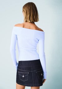 Svetlo modrý rebrovaný top s odhalenými ramenami, doplnený tmavými rifľovými mini sukňami, ktoré majú dve zadné vrecká a kontrastné švy.