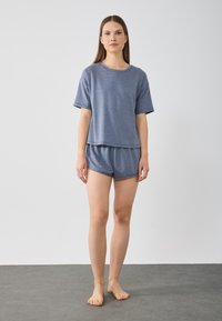 Graues, kurzärmeliges Oberteil und passende Shorts aus einem weichen, leichten Stoff. Das Outfit zeichnet sich durch eine lockere Passform und ein schlichtes Design aus.