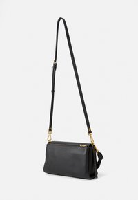 Sort læder crossbody taske med en struktureret form, guld hardware detaljer og en justerbar rem. Har en lynlåslukning i toppen.