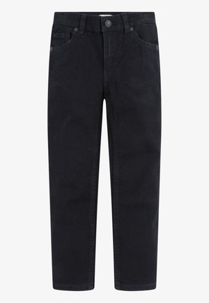Jean noir à jambe droite avec bouton sur le devant, fermeture éclair et design cinq poches sur fond blanc uni.