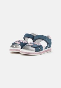 Sandalias infantiles de ante azul con aplicaciones florales rosas, correas ajustables y una suela blanca brillante. Diseño abierto para mayor transpirabilidad.