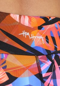 Colorful activewear waistband in orange, pink, and blue abstract leaf pattern, with black trim and “Hey Honey” logo in white script.