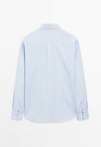 Lichtblauwe blouse met lange mouwen, zichtbaar vanuit de achterkant, met een klassieke kraag en knopenmanchetten op een witte achtergrond.