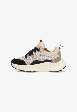 Sneaker featuring a beige upper with silver glitter accents, black suede overlays, textured tan heel, and a thick white sole with a patterned tread.