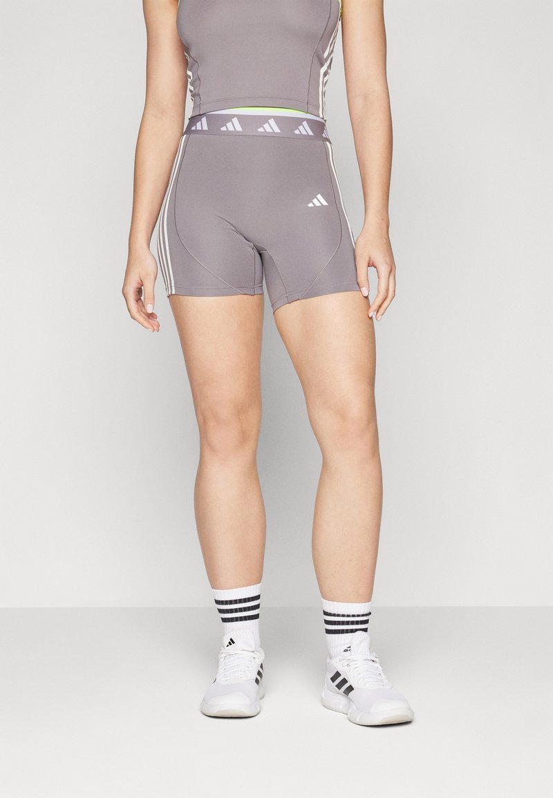 Shorts atletici gri cu dungi albe și un tiv asortat. Materialul este neted și elastic, conceput pentru îmbrăcăminte sportivă.