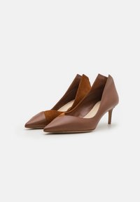 Zapatos de tacón alto de cuero marrón y gamuza con punta afilada y diseño recortado, que cuentan con un tacón de 3 pulgadas y una textura suave.