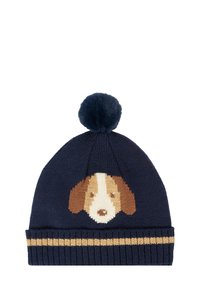 Un bonnet tricoté en bleu foncé avec un motif de visage de chien en beige et marron. Il présente un pompon en laine doux de couleur marine et une bande rayée dorée au bas.