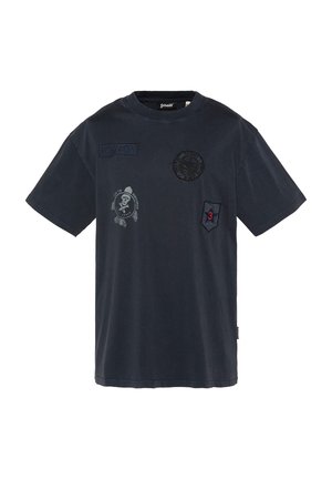 T-shirt bleu marine foncé à manches courtes avec plusieurs patches noirs, dont un emblème de crâne, un patch "US 740 N" et un badge rouge numéro 3.