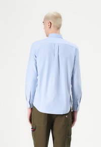 Lichtblauwe overhemd met lange mouwen, een button-down kraag, een rugplooien en met knoopmanchetten, gecombineerd met olijfgroene cargo-broeken met zakken.