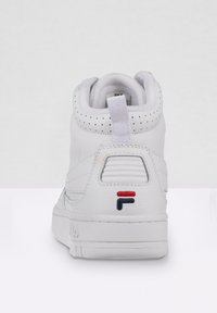 Deportiva alta blanca hecha de cuero con detalles perforados, un diseño texturizado y un logo en rojo, blanco y azul en el talón.
