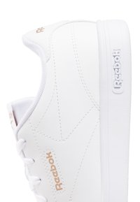 Białe sneakersy Reebok z gładką syntetyczną cholewką, teksturowanym przeszyciem i subtelnym logo w różowym złocie. Widoczne są sznurówki oraz wyściełany kołnierz.