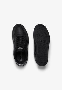 Zapatillas negras con parte superior de cuero suave, punta redondeada, suela de goma negra texturizada y un destacado detalle de logo en el panel lateral.