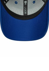 Blaue Kappe mit einem schwarzen Unterrand, strukturiertem Design und kontrastierenden Nähten. Innen hat sie ein graues Futter mit Markeninformationen.