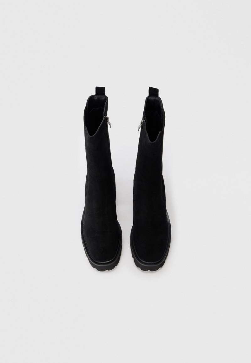 Botines de ante negro con un acabado suave, que presentan un diseño elegante, cremalleras en los laterales y una suela de goma gruesa para mayor durabilidad.
