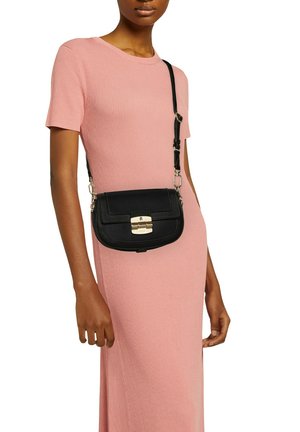 Sac en cuir noir porté en bandoulière avec une forme rectangulaire, matériel en or et détails cousus ; porté avec une robe rose à côtes.