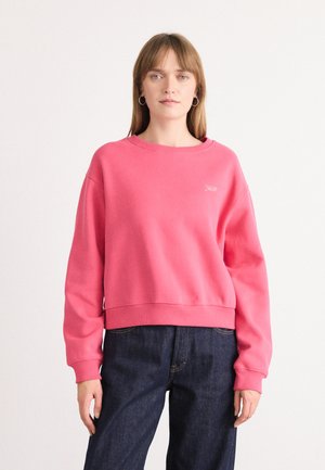 Felpa rosa a maniche lunghe con scollatura rotonda e polsini a costine. Abbinata a pantaloni in denim blu scuro. Semplice dettaglio ricamato sul petto.