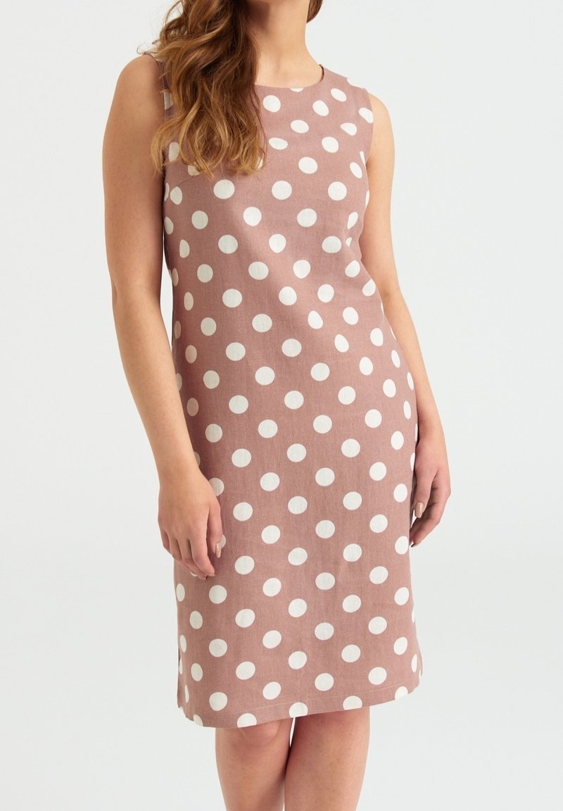 Une robe sans manches en tissu rose pâle ornée de grands pois blancs, avec une silhouette droite et un ourlet arrivant au genou.