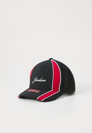Gorra de béisbol negra con rayas rojas y blancas, con "Jordan" bordado en la parte frontal y "1984" en la visera. Fabricada con tela texturizada.