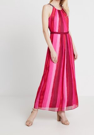 Vestido sin mangas hasta el tobillo con rayas verticales en tonos rosa y rojo, cintura ajustada, combinado con zapatos de tacón ancho abiertos en color nude.