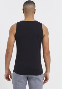 Zwart mouwloos tanktop van gladde stof, met een relaxte pasvorm en afgeronde zoom, gecombineerd met grijze textuur sportbroeken.