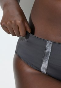 Ciemnoszare spodenki kąpielowe z błyszczącym srebrnym panelem na środku. Charakteryzują się gładką teksturą i dopasowanym krojem. Ręcznie regulowany pasek w talii.