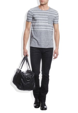 Camiseta de rayas gris con mangas cortas, combinada con jeans negros y botas negras. Sosteniendo un gran bolso de cuero negro.