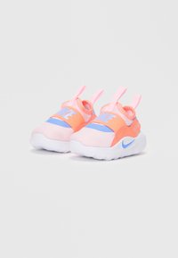 Nike otroške teniske z roza mrežastim zgornjim delom, modrim poudarjanjem in belim gumijastim podplatom, z elastičnimi trakovi za enostavno obuvanje.