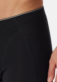 Schwarze sportliche Leggings mit glatter Textur, die an der Taille einen grauen Akzent sowie Flachnähte für Komfort und Flexibilität aufweisen.