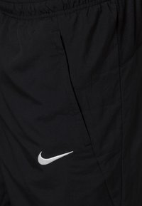Czarne szorty sportowe z lekkiego materiału, z elastycznym pasem, bocznymi kieszeniami oraz białym logo Nike z przodu.