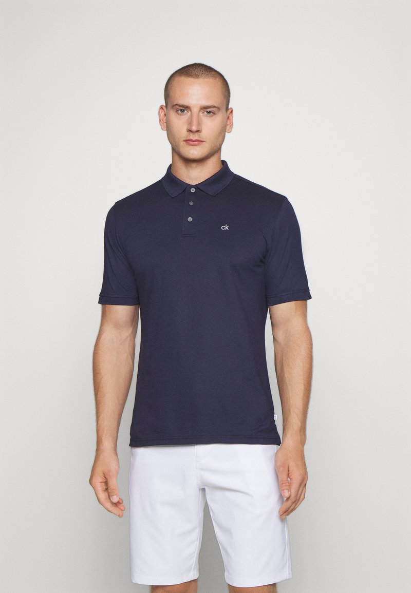 Navy blue polo shirt in a cotton blend, featuring a three-button placket and short sleeves. Small embroidered logo on the chest.