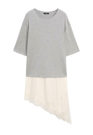 Grå kortærmet top lagdelt over asymmetrisk cremet blonde nederdel med blomsterbroderi og bølget kant.