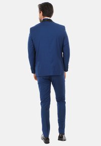 Completo blu a due pezzi con una vestibilità su misura, caratterizzato da un collo nero a contrasto e pantaloni coordinati. Tessuto liscio con leggera lucentezza.