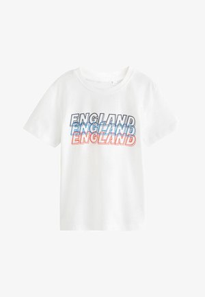 Biele tričko s krátkym rukávom so slovom "ENGLAND" vytlačeným trikrát v prekrytých čiernych, modrých a červených kontúrovaných písmenách na prednej strane.