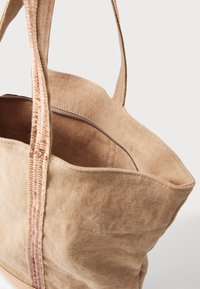 Besi kanvos tote maišelis su erdvia vidine dalimi, turi užtrauktuko uždarymą ir dvi pintas rankenas nešimui. Textūruotas audinys ir minkštas paviršius.