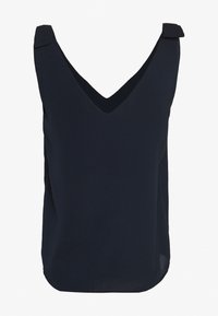 Tmavě modrý top bez rukávů s výstřihem do V, který má mírně robustní ramenní popruhy a jemnou, splývavou látku s hladkou texturou.