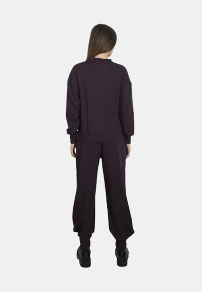 Set di abbigliamento da casa viola composto da un pullover corto con polsini a coste e pantaloni larghi con caviglie elastiche, realizzato in un tessuto morbido.