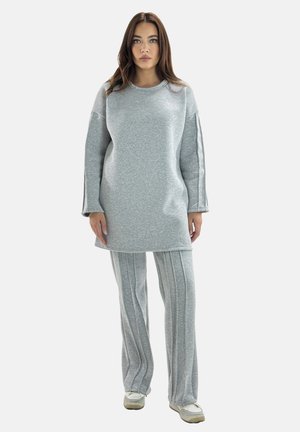 Tunic a maniche lunghe di un grigio chiaro con texture a coste, abbinata a pantaloni dritti a righe coordinati. Tessuto morbido, vestibilità rilassata, design casual.