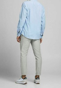 Svetle modrá košile s dlouhým rukávem a ohrnutými rukávy. Světle šedé zúžené kalhoty. Bílé tenisky s námořnickými prvky a hnědými podrážkami.