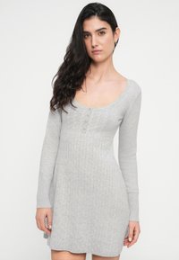 Γκρι πλεκτό φόρεμα με ανάγλυφη υφή ριμπ, μακριά μανίκια, στρογγυλή λαιμόκοψη και σειρά από κουμπιά. Απλός σχεδιασμός και ελαφρύ υλικό.