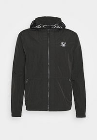 Zwarte lichte jas met een ritssluiting aan de voorkant, voorzien van een capuchon gevoerd met een merkpatroon en een klein logo op de borst.