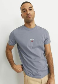 Tricou scurt, de culoare bleu deschis, realizat dintr-un amestec de bumbac, cu logo-ul "R.D.D." și un punct roșu mic pe față, textură netedă, croială clasică.